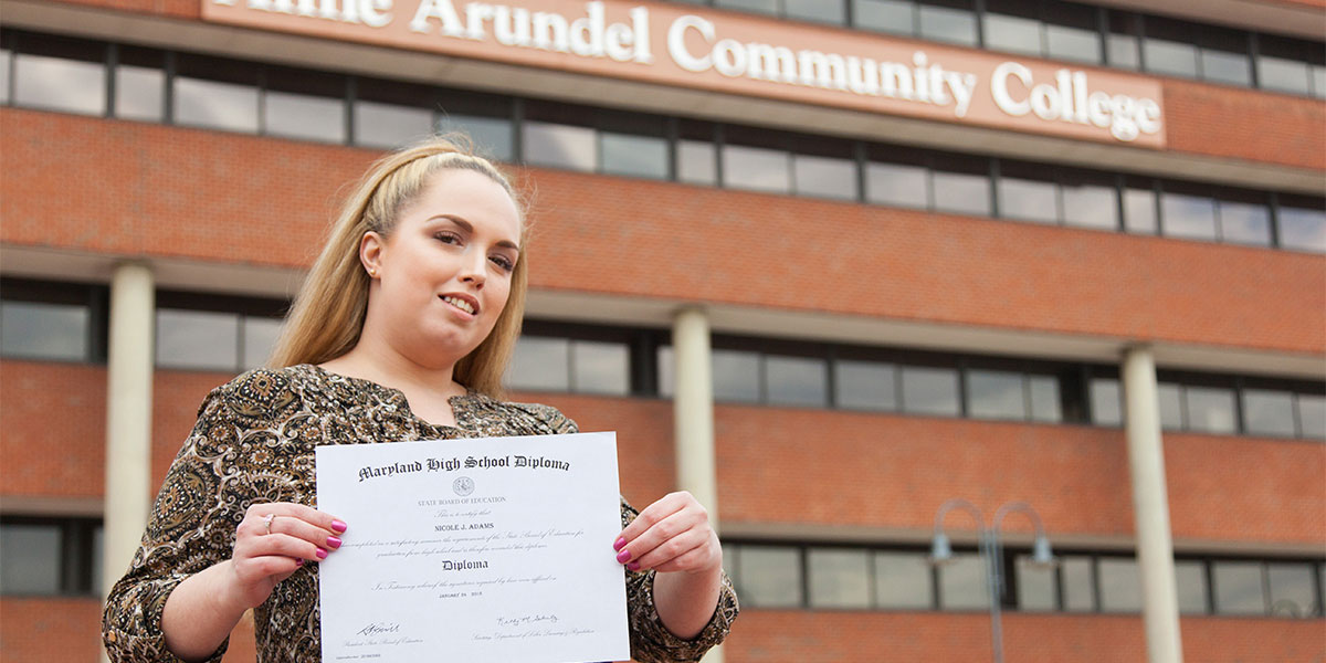 Nicole holding up her high school certificate