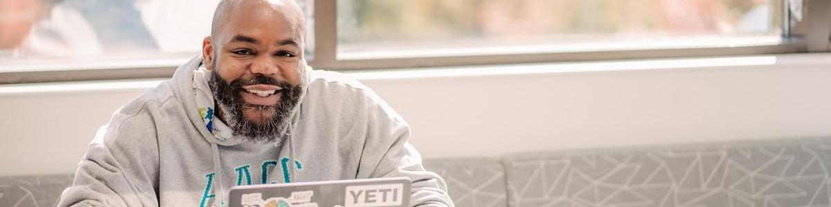 Student smiling for camera while sitting at table