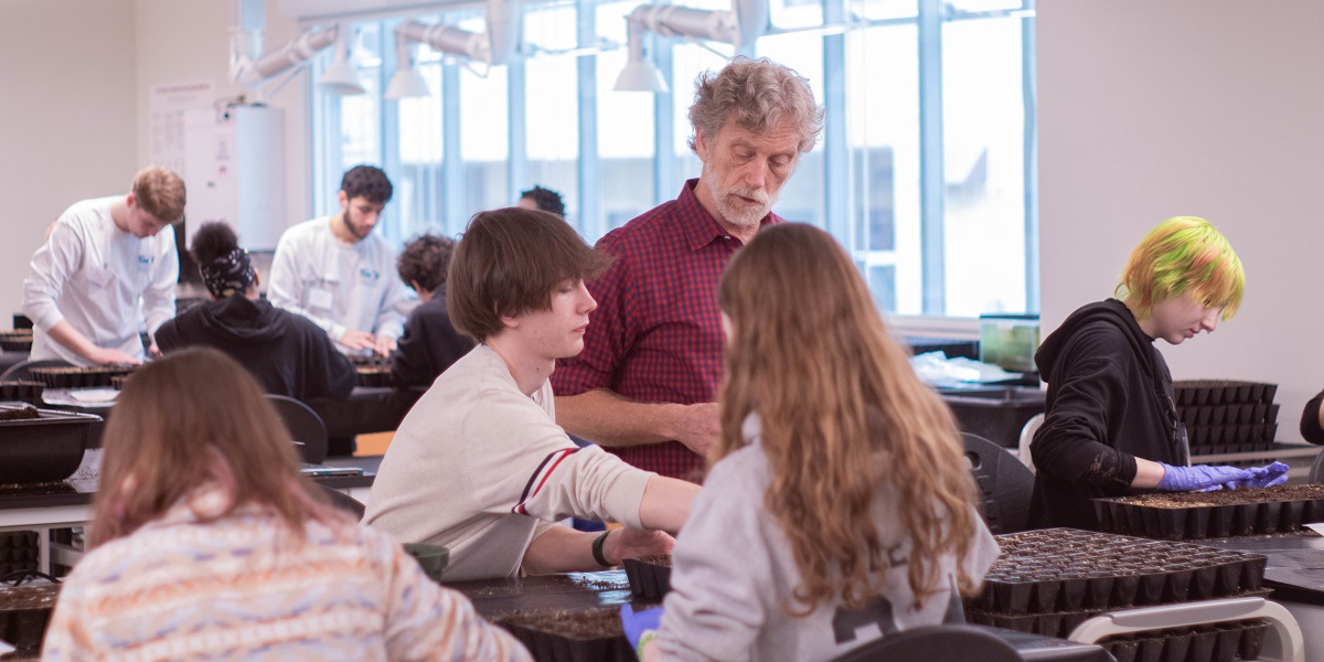 AACC faculty member oversees students planting seedlings.