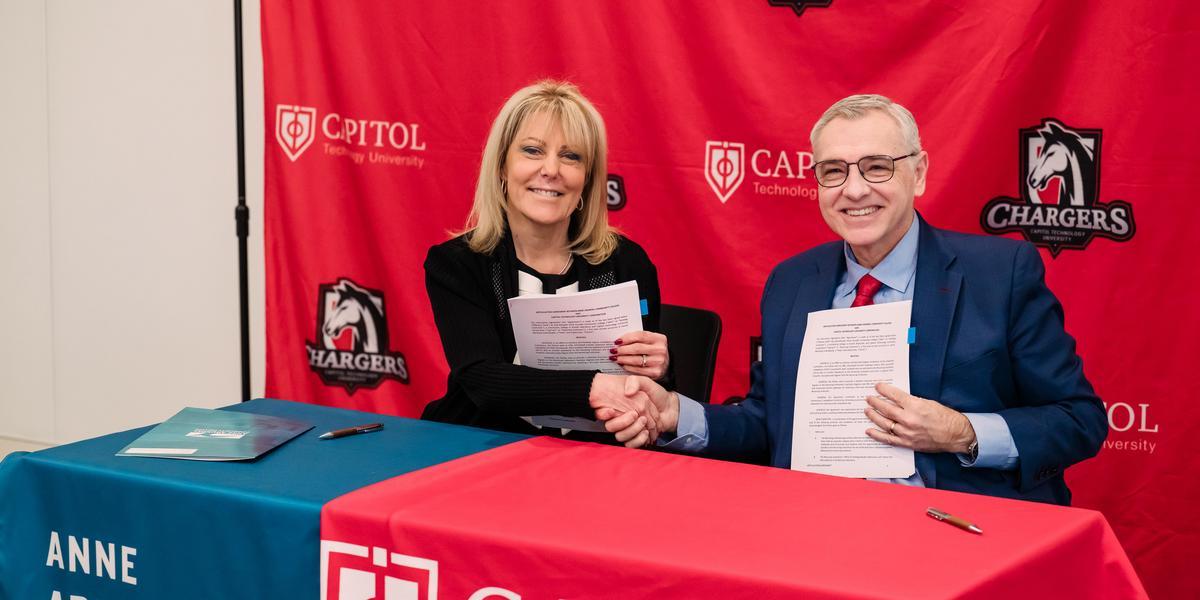Presidents of Capitol Technology University and AACC hold up signed articulation agreements.