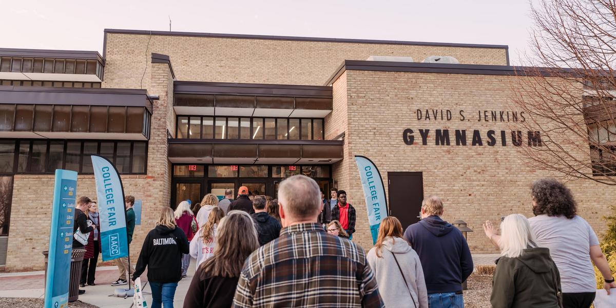 Crowd of people walking into the gym. Banners that say 