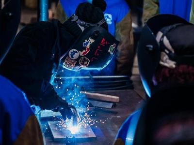 Instructor Jannah Madyun demonstrates welding to a class of students.