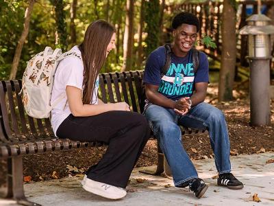 Two students sitting on a bench talking.