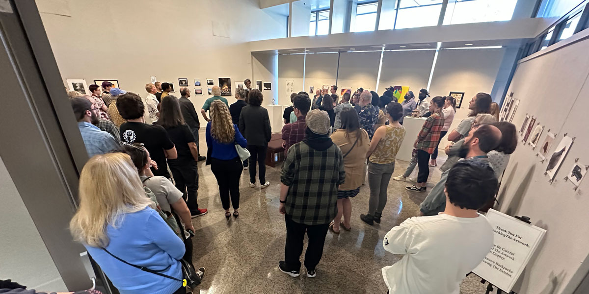 Inside the CADE Art Gallery with people looking at the art.