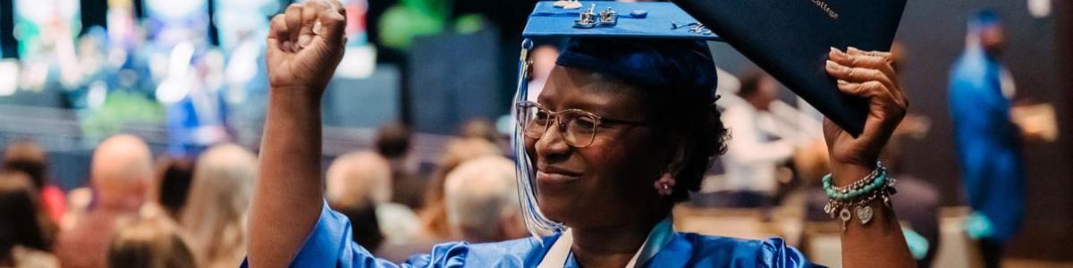 Student wearing regalia with their diploma