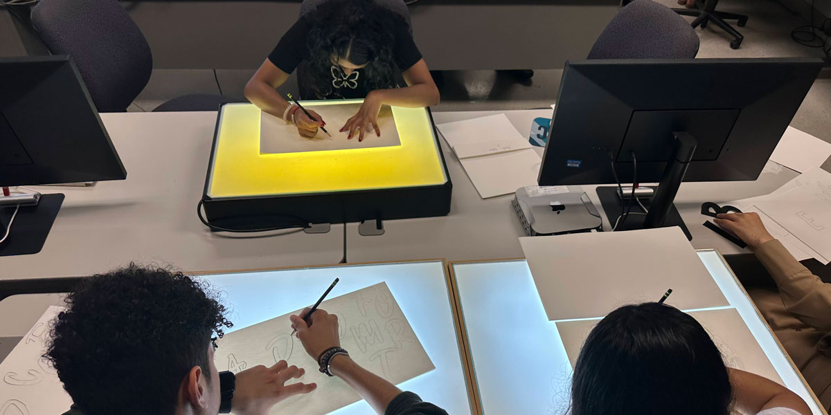 Students tracing a drawing over a light.