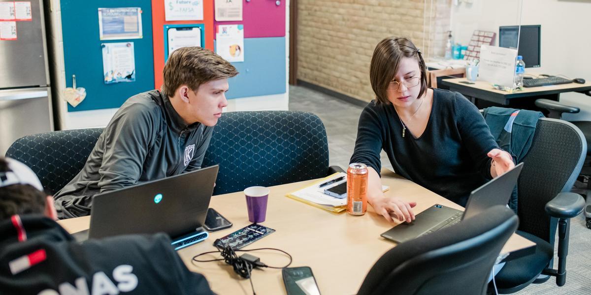 Two people looking at a computer and talking