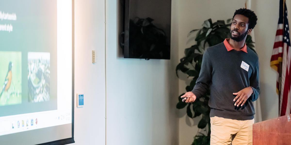 A student stands at a podium during a presentation.