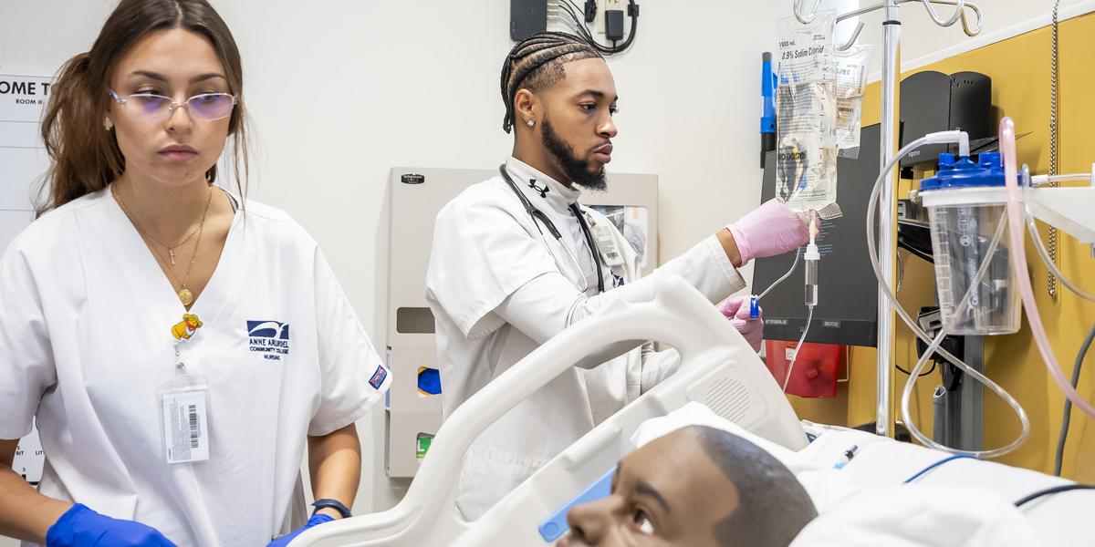 Nursing student working with machine in simulation lab.