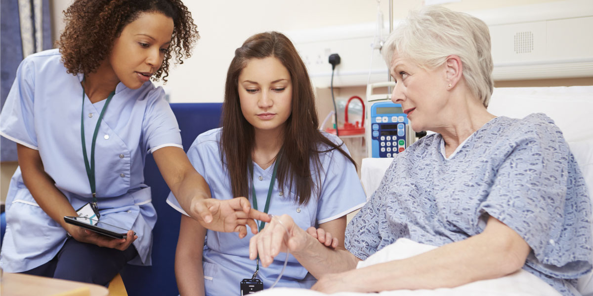 Health care students at the bedside of a patient.