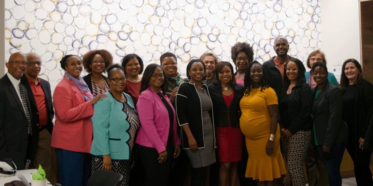 Group of AACC employees smiling and posing inside a room.