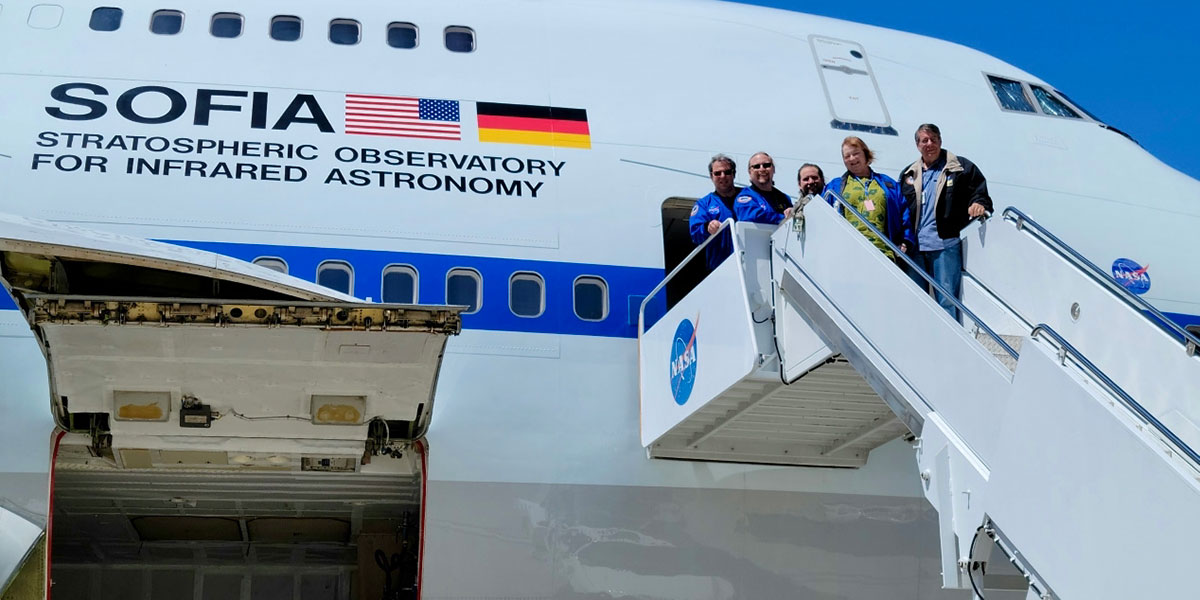 Deborah Levine standing at the top of a ladder next to a plane for the Stratospheric Observatory for Infrared Astronomy