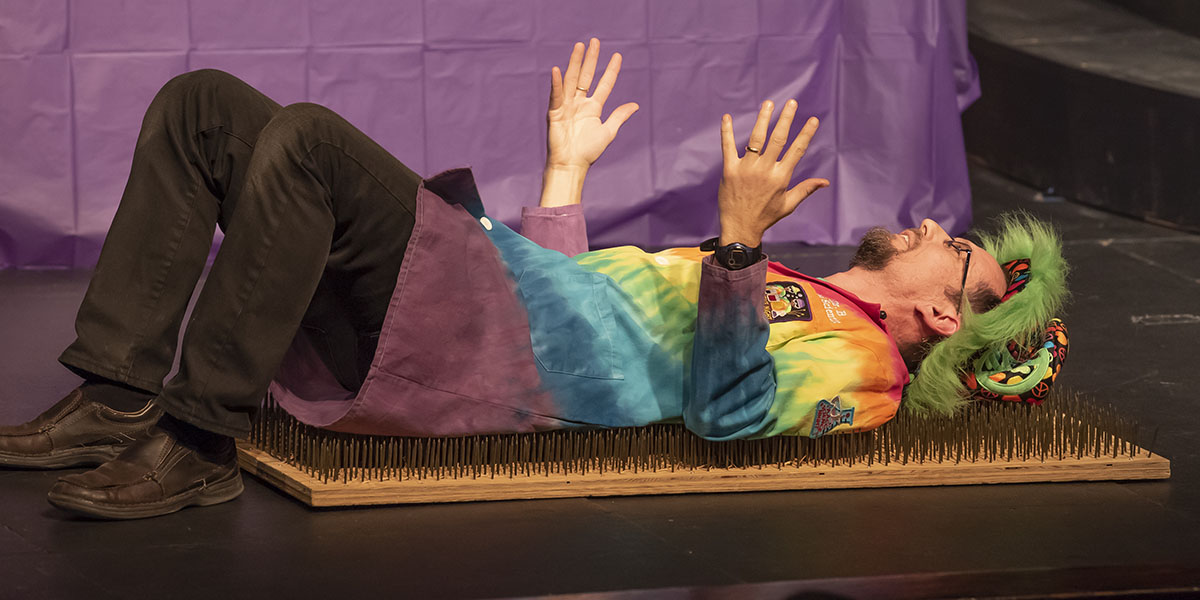 Jason Barbour laying on a bed of nails