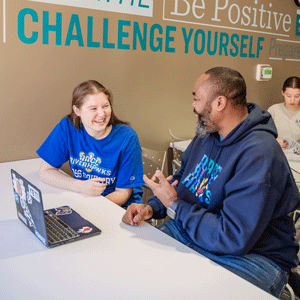 Students smiling with laptop in front of them