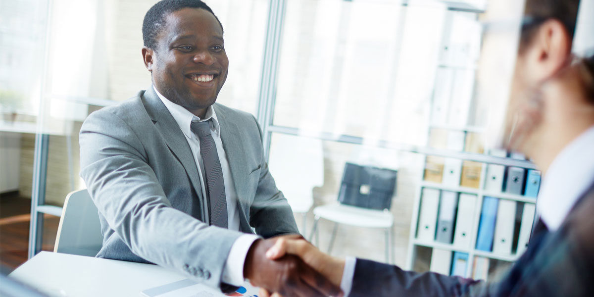 Male student shakes the hand of an employer at a job interview.