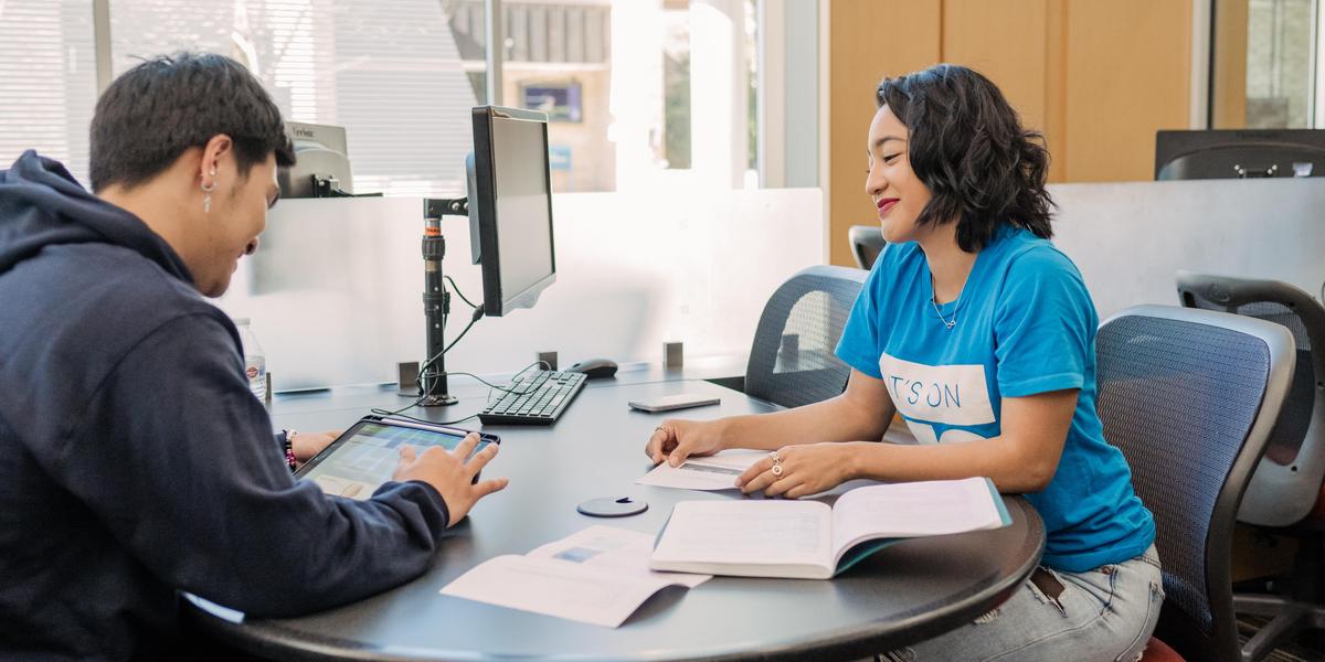 Students talking to one another at a desk.