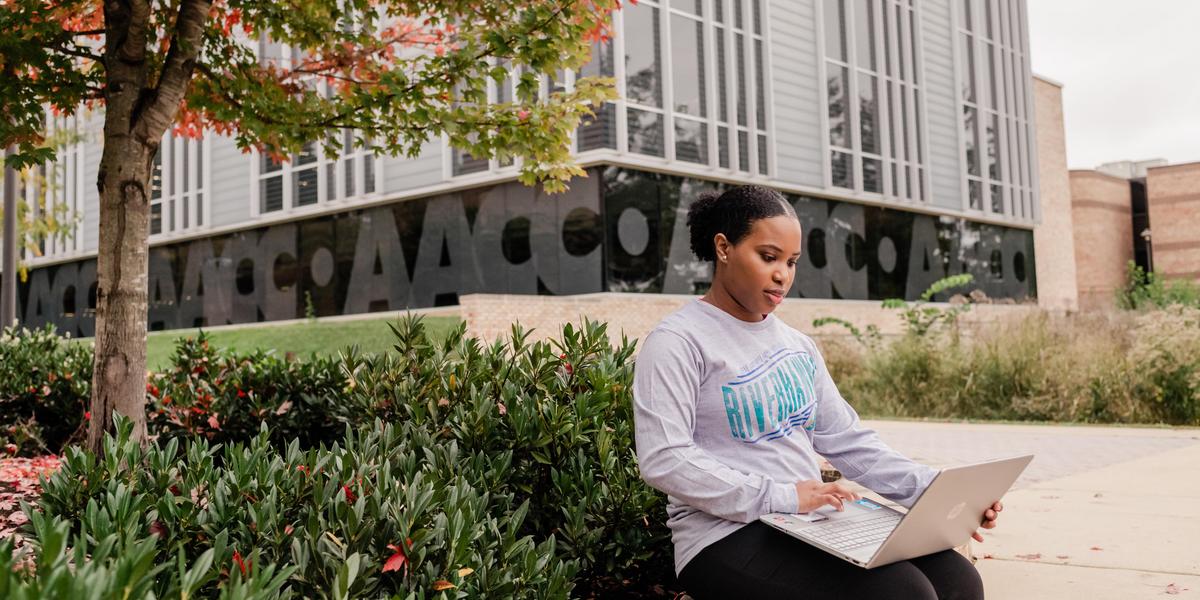 AACC student with laptop outside the library.