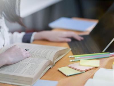 Student refers to textbook and laptop.