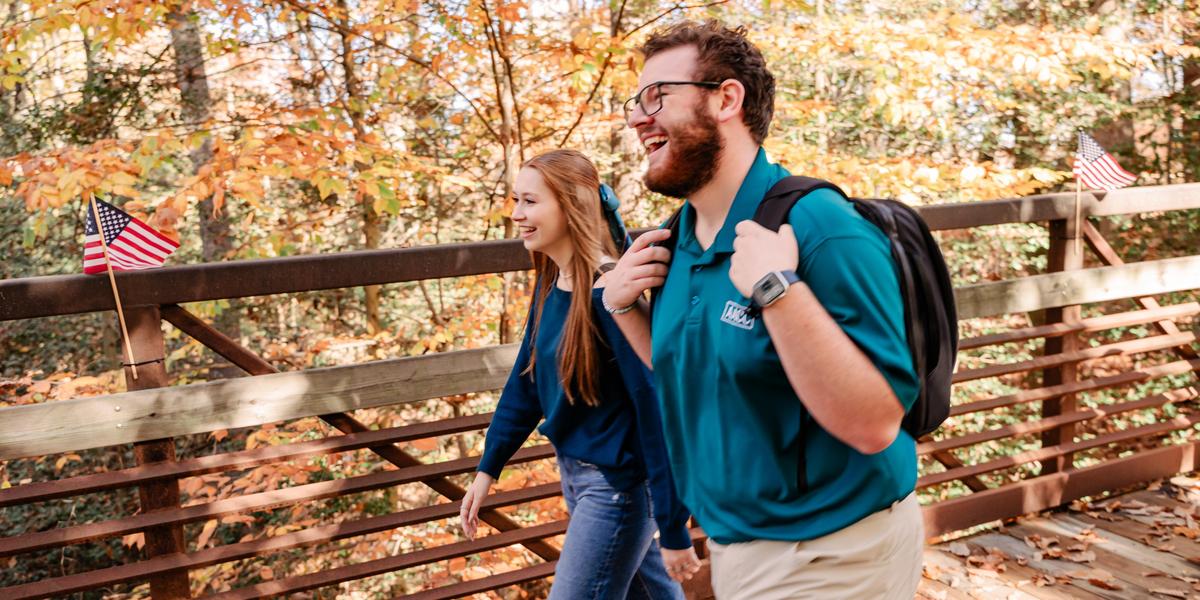 Students smiling and laughing while walking across bridge.