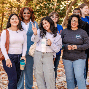 Students posing outside with an autumn background.