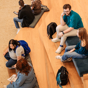 Students in different groups, sitting and talking.