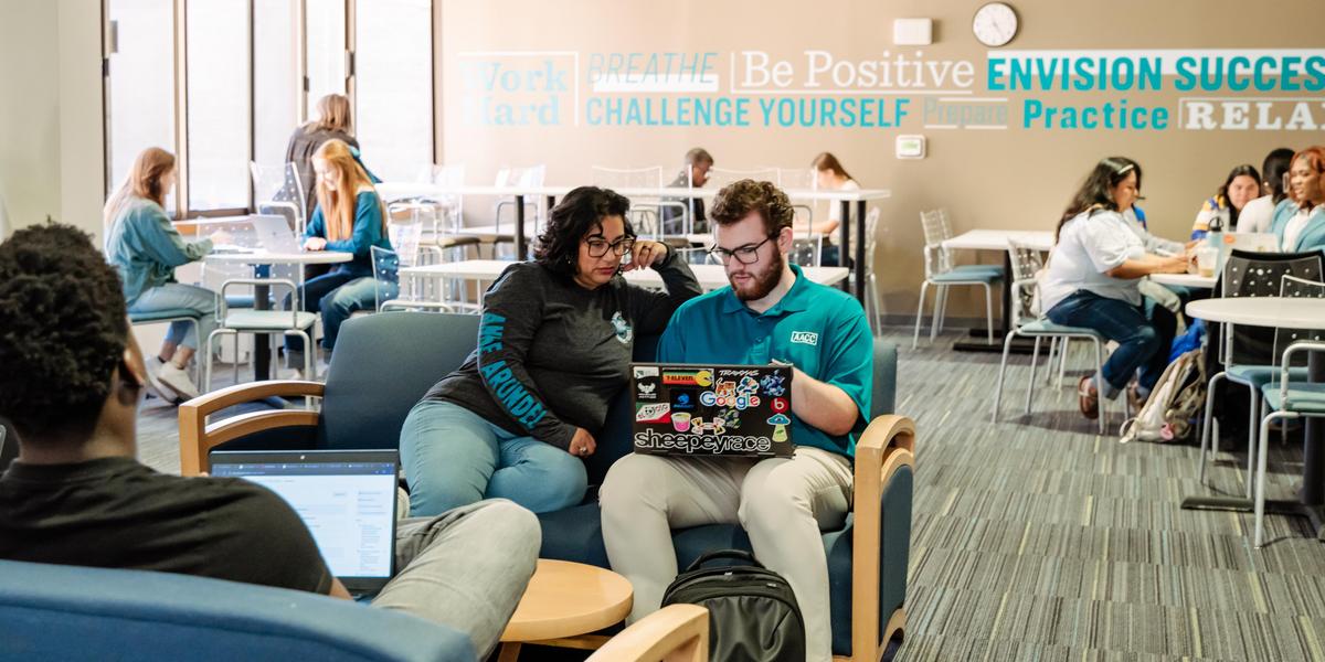 Students looking at computers together in a study space.