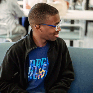 Student sitting inside on a couch.